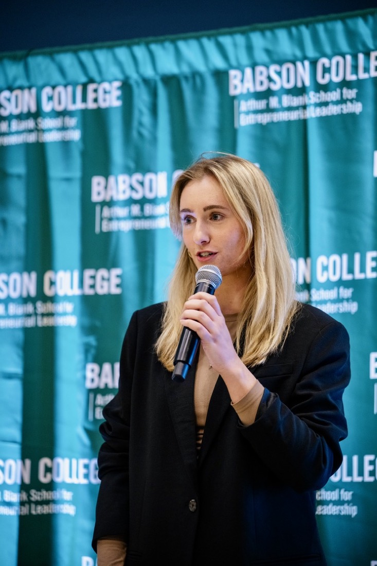 Anna speaking into a microphone at a Babson College event