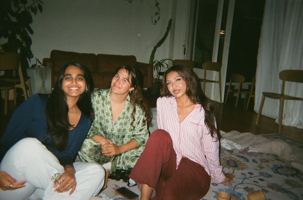 Three women in pyjamas sitting together on the floor, laughing, at a Cherry pyjama party